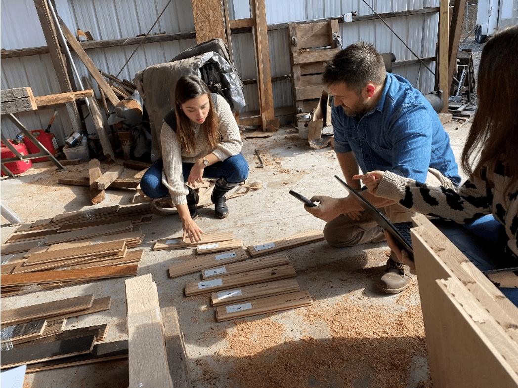 Mark Bowe inspecting wood samples with an AHF rep for the Barnwood Living collection of barnwood floors