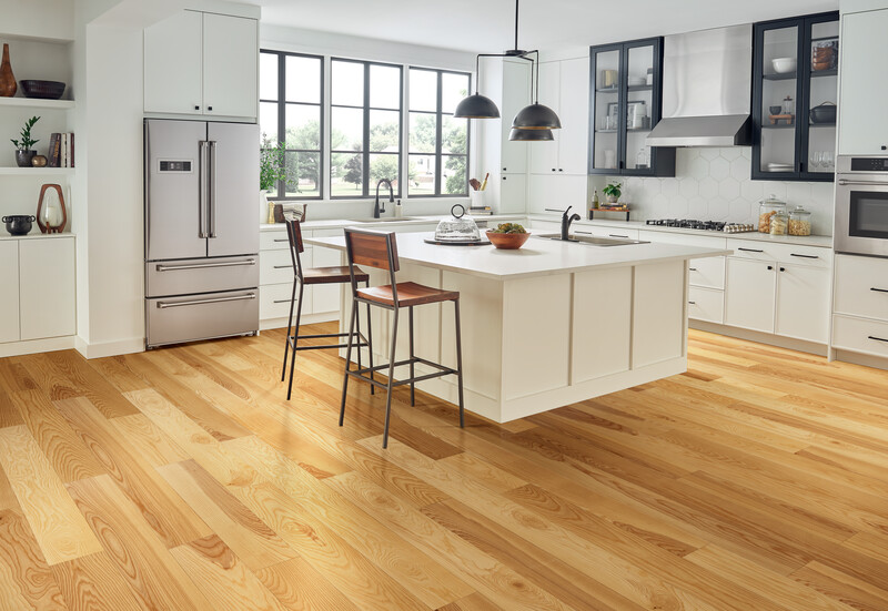Kitchen with a white island and stools with light white oak flooring