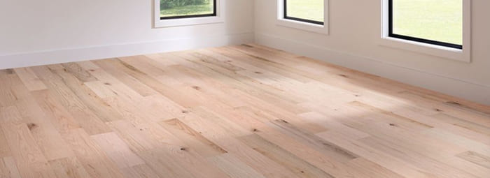 Light hardwood flooring installed in a bright room with large windows.