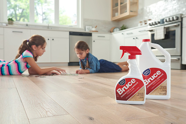 Girls playing with a puzzle on floor with bottles of Bruce hardwood flooring cleaners