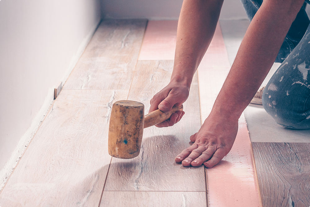 man hitting hardwood floors with a mallet